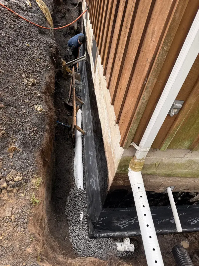 Open French drain trench with gravel and perforated pipe in a New York backyard