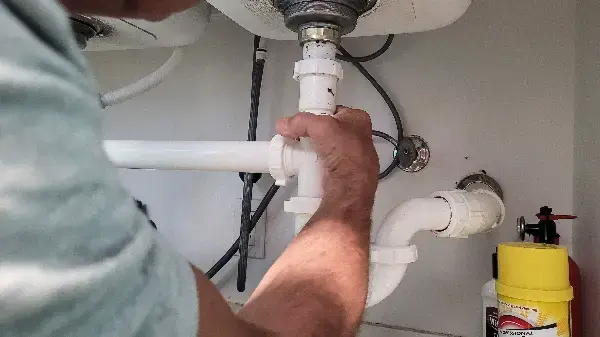 Plumber installing new supply lines under a bathroom vanity in a New York home